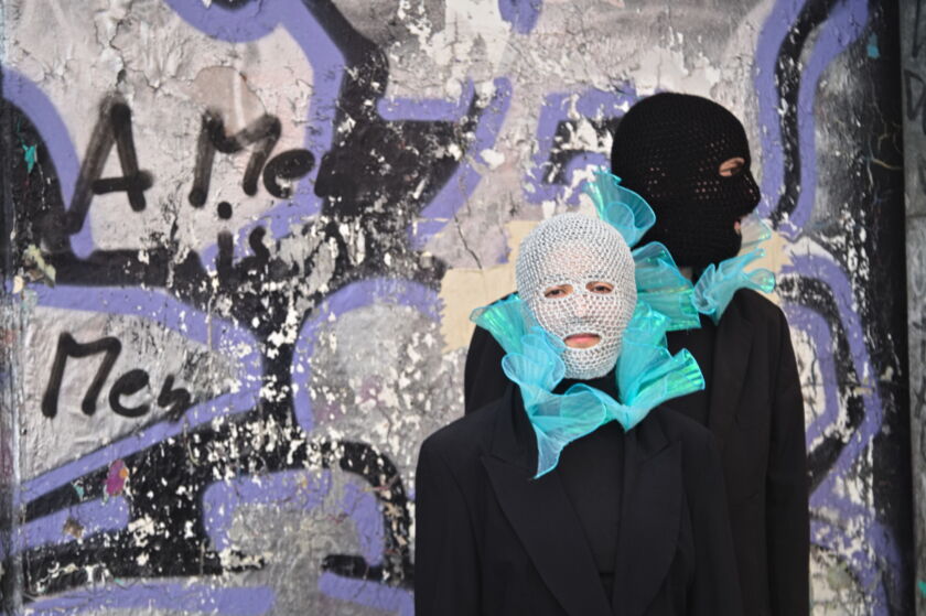 two people wearing balaclavas with a graffiti background